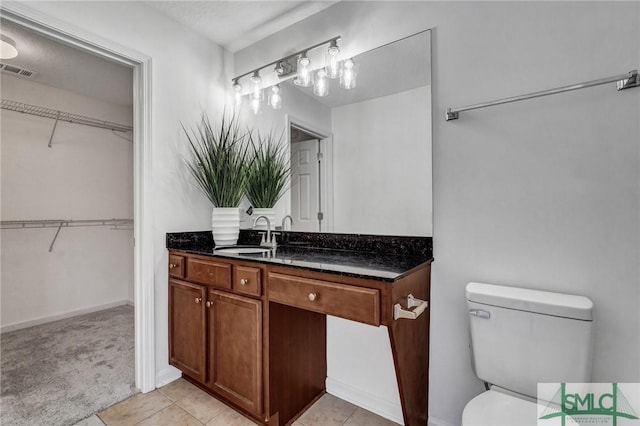 full bathroom featuring visible vents, toilet, tile patterned floors, a spacious closet, and vanity