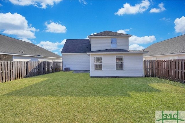 back of property with a fenced backyard, a yard, and central AC unit