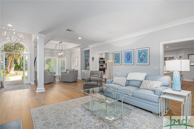 living area featuring visible vents, ornate columns, a chandelier, and crown molding
