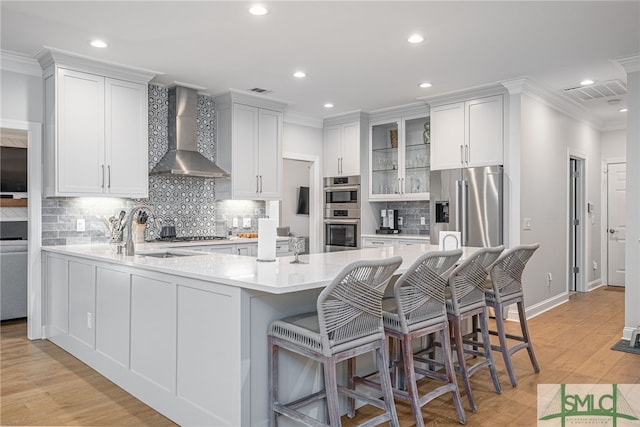 kitchen featuring wall chimney range hood, stainless steel appliances, and recessed lighting