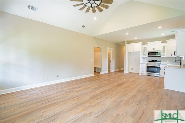 unfurnished living room with high vaulted ceiling, light wood-style flooring, visible vents, and baseboards