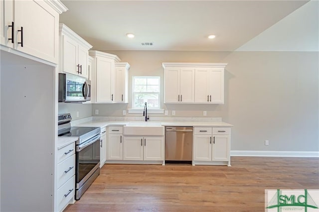 kitchen featuring stainless steel appliances, light countertops, visible vents, white cabinetry, and a sink