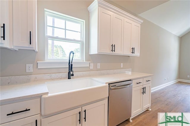 kitchen featuring stainless steel dishwasher, white cabinetry, a sink, light wood-type flooring, and baseboards