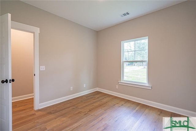 spare room featuring light wood-type flooring, baseboards, and visible vents