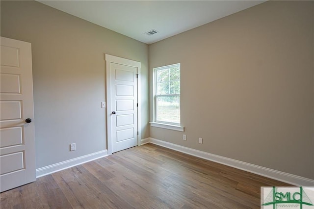 spare room featuring visible vents, baseboards, and wood finished floors