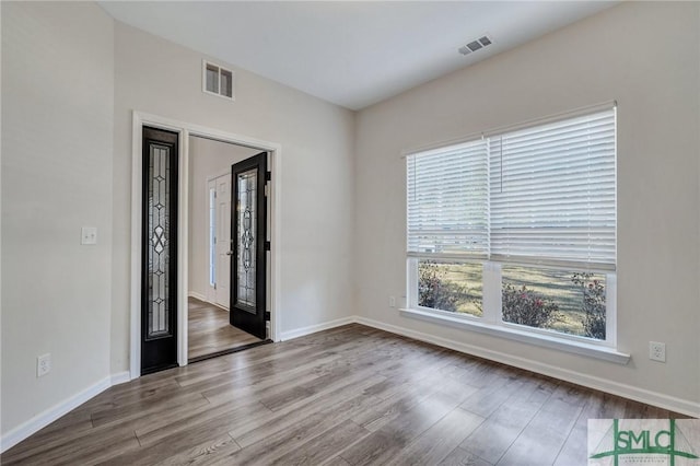 empty room with visible vents, baseboards, and wood finished floors