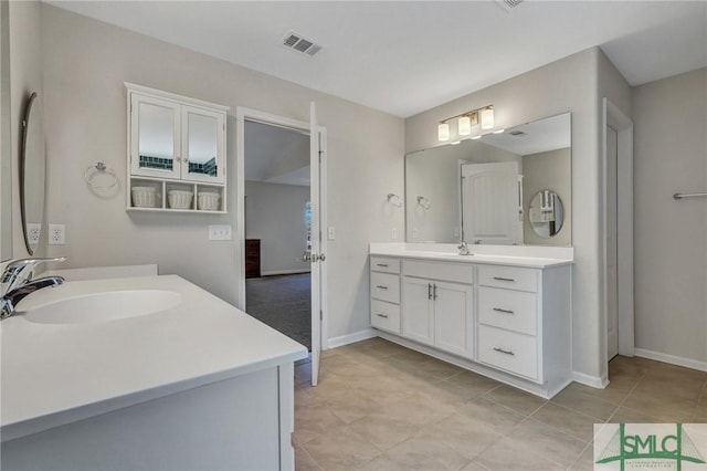 full bath featuring two vanities, baseboards, visible vents, and a sink