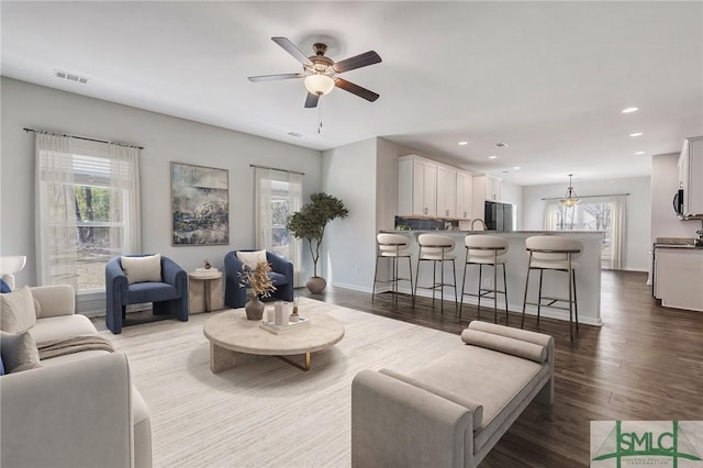 living area with recessed lighting, visible vents, a healthy amount of sunlight, and wood finished floors