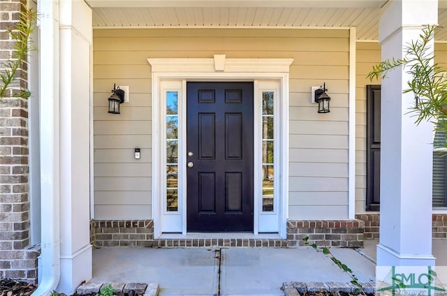 entrance to property featuring covered porch and brick siding