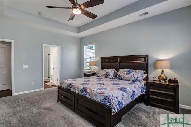 bedroom with carpet, a raised ceiling, visible vents, ceiling fan, and baseboards