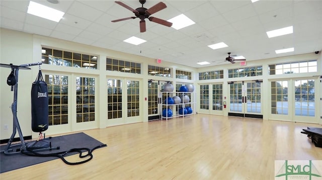 exercise area featuring ceiling fan, a paneled ceiling, a high ceiling, wood finished floors, and french doors