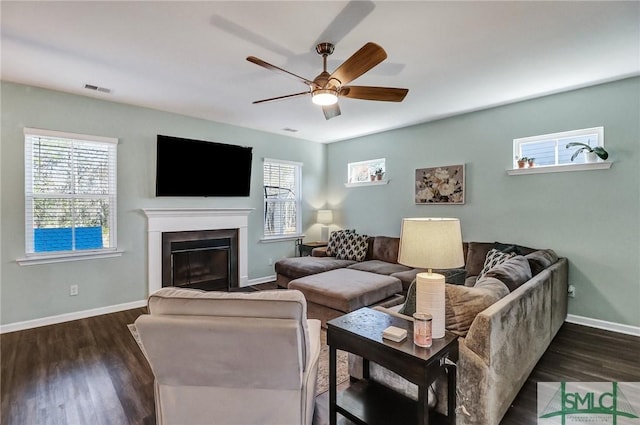 living area featuring a fireplace with flush hearth, visible vents, baseboards, and dark wood-style floors