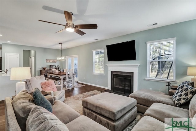 living room with baseboards, visible vents, a ceiling fan, a fireplace with flush hearth, and dark wood-type flooring