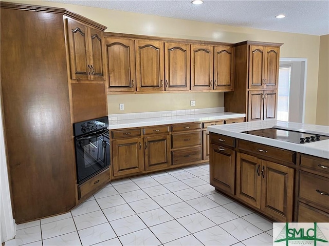 kitchen with tile counters, a textured ceiling, and black appliances