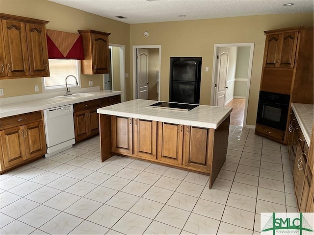 kitchen with a center island, a sink, tile countertops, and black appliances