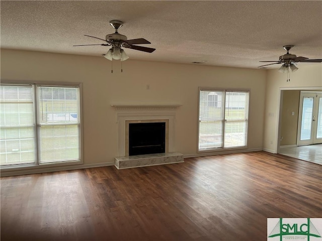 unfurnished living room featuring a fireplace with raised hearth, ceiling fan, french doors, and wood finished floors