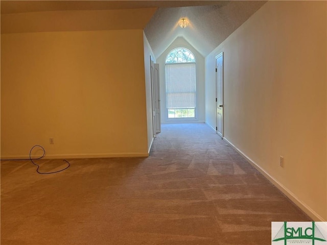 hall with vaulted ceiling, carpet, and baseboards