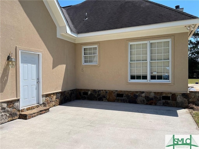 exterior space featuring roof with shingles, a patio, and stucco siding