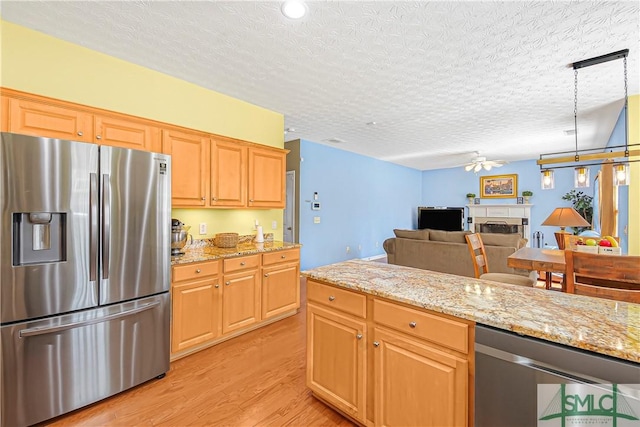 kitchen with a ceiling fan, stainless steel refrigerator with ice dispenser, light wood finished floors, and light stone countertops