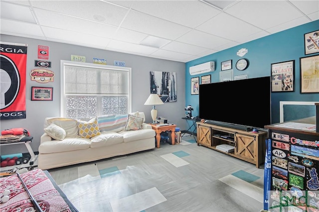 living area with a drop ceiling and a wall unit AC