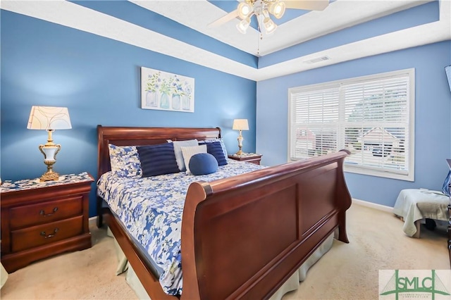 carpeted bedroom featuring baseboards, visible vents, a raised ceiling, and a ceiling fan