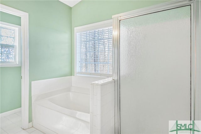 bathroom with a stall shower, tile patterned floors, a bath, and baseboards