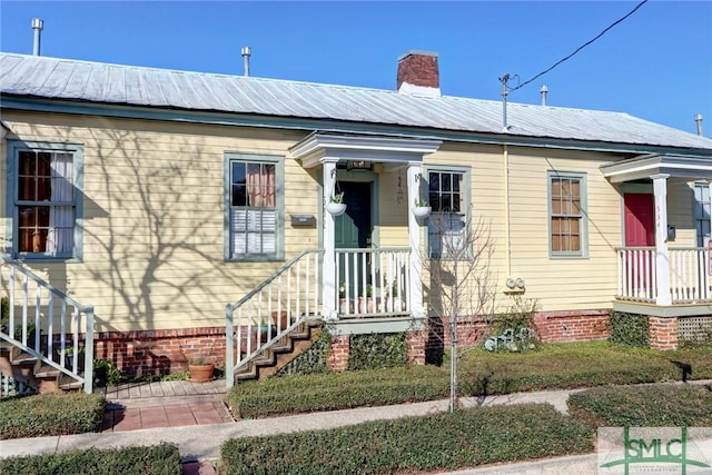 view of front of house featuring metal roof and a chimney