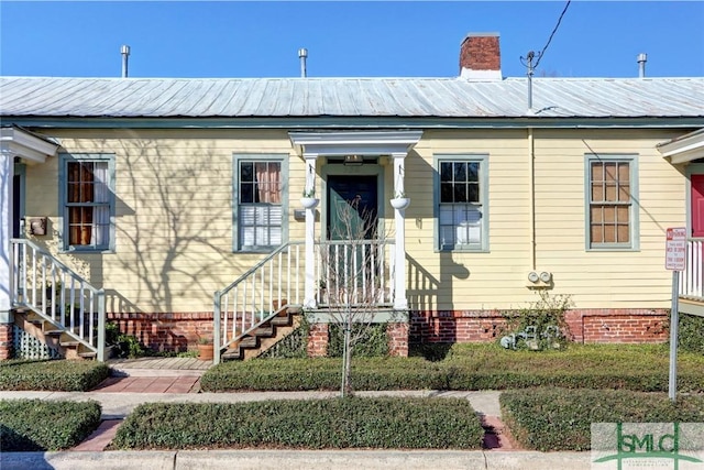 bungalow featuring metal roof and a chimney