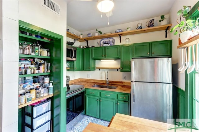 kitchen with visible vents, green cabinetry, stainless steel appliances, open shelves, and a sink