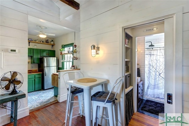 dining area with hardwood / wood-style flooring, ceiling fan, and wooden walls