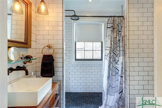 full bathroom featuring tile walls, tiled shower, and vanity