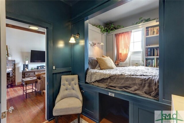 bedroom with a brick fireplace and wood finished floors