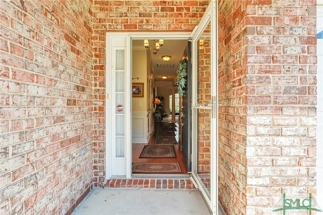 doorway to property featuring brick siding and visible vents