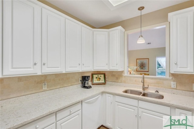 kitchen with white dishwasher, a sink, white cabinets, backsplash, and decorative light fixtures