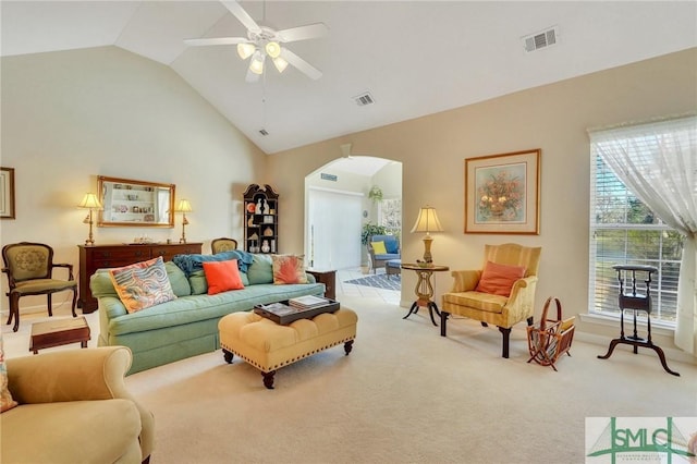 living area featuring arched walkways, carpet floors, high vaulted ceiling, and visible vents