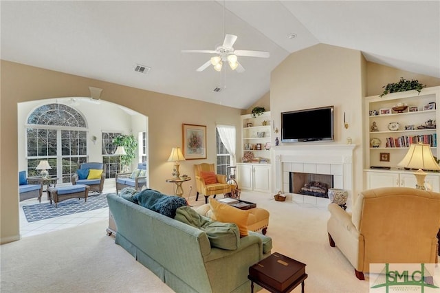 living area with light carpet, built in shelves, visible vents, and a tile fireplace