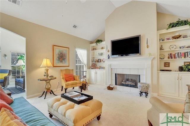 carpeted living area with a healthy amount of sunlight, built in shelves, visible vents, and a fireplace