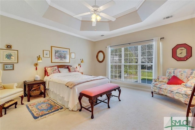 carpeted bedroom featuring ornamental molding, a tray ceiling, visible vents, and ceiling fan