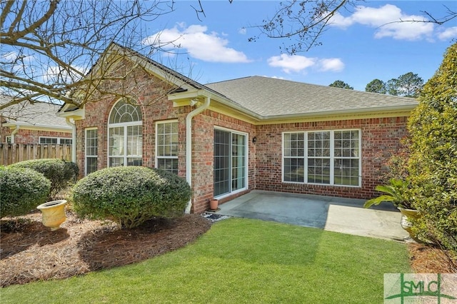 back of house featuring brick siding, a yard, roof with shingles, a patio area, and fence