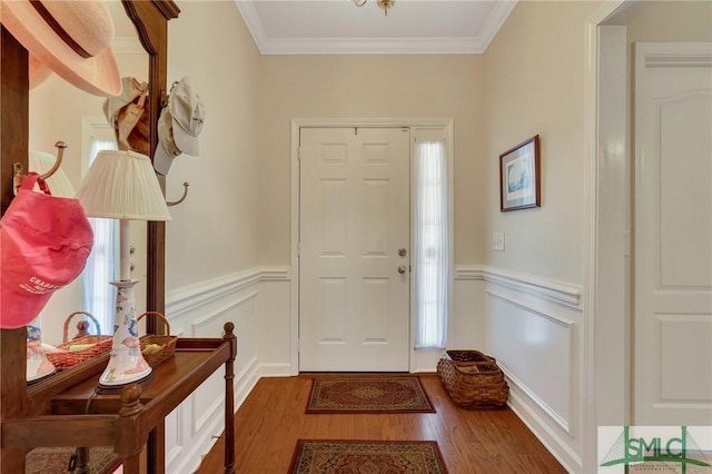 foyer entrance featuring ornamental molding, a wainscoted wall, and wood finished floors