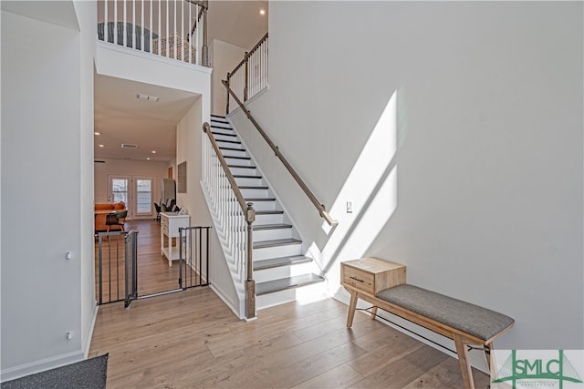 entrance foyer featuring stairs, light wood finished floors, a high ceiling, and baseboards