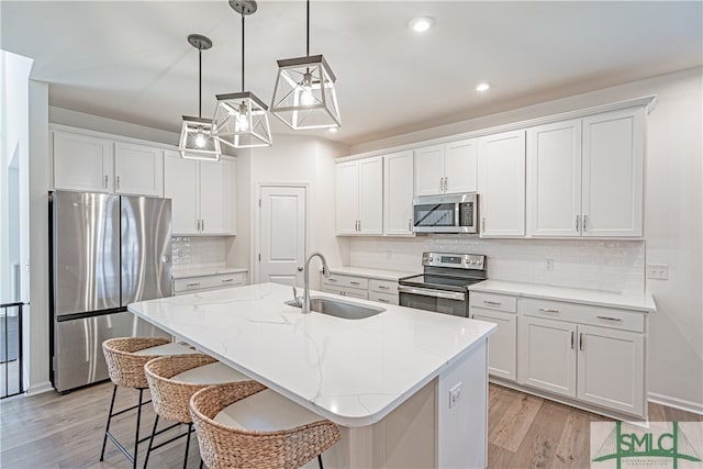 kitchen featuring white cabinets, light wood finished floors, stainless steel appliances, and a sink