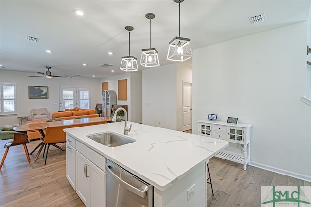 kitchen with visible vents, white cabinets, dishwasher, light wood-style floors, and a sink