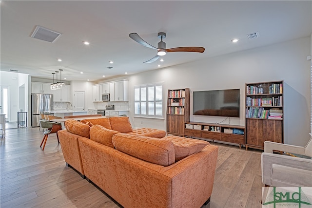 living area with light wood-style flooring, visible vents, a ceiling fan, and recessed lighting