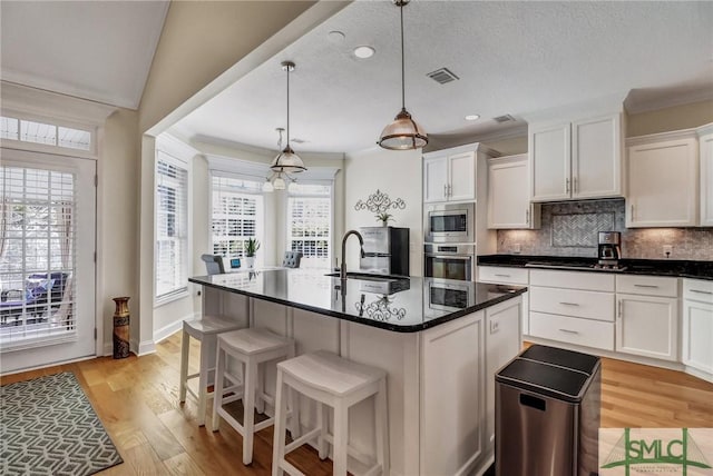 kitchen with appliances with stainless steel finishes, white cabinets, a sink, and decorative backsplash