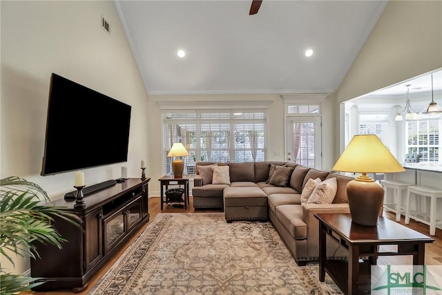 living area with high vaulted ceiling, visible vents, plenty of natural light, and light wood-style flooring