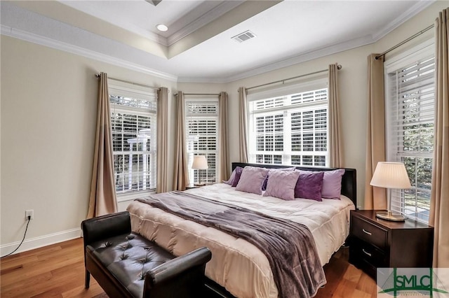 bedroom featuring multiple windows, wood finished floors, visible vents, and crown molding