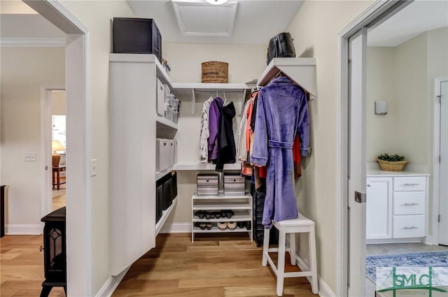 walk in closet with attic access and wood finished floors