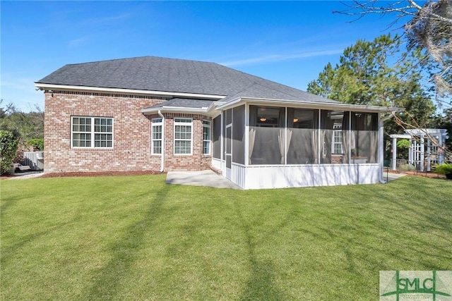 back of property with a yard, brick siding, and a sunroom