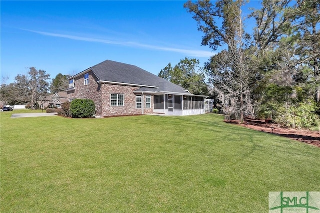 rear view of house featuring a yard, brick siding, and a sunroom